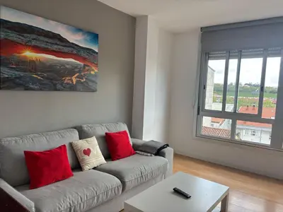 a living room with a couch and a large window at Amplio piso con vistas en la entrada del camino C4 in Santiago de Compostela