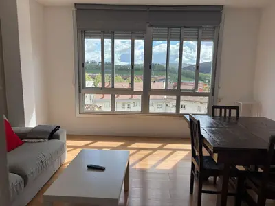 a living room with a table and a large window at Amplio piso con vistas en la entrada del camino C4 in Santiago de Compostela