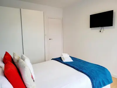 a bedroom with a white bed with red and blue pillows at Amplio piso con vistas en la entrada del camino C4 in Santiago de Compostela