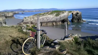 a bike is chained to a pole on a beach at Apartamentos Rurales San Xillao in Ribadeo