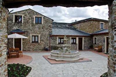a courtyard with a fountain in front of a stone building at Apartamentos Rurales San Xillao in Ribadeo