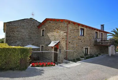 a brick building with red flowers in front of it at Apartamentos Rurales San Xillao in Ribadeo