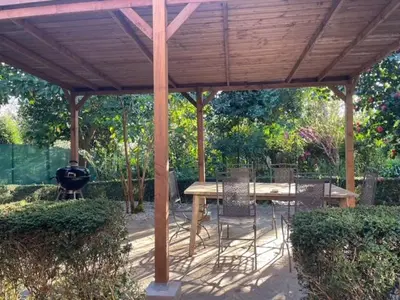 a wooden pavilion with a table and chairs under it at Casa Do Bosque in Cabañas