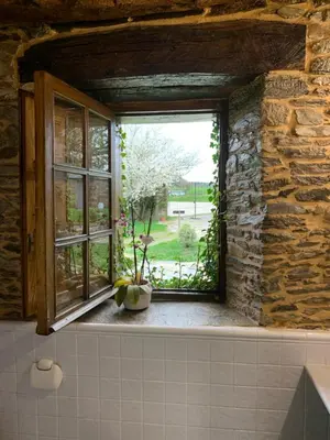 a window in a stone building with a vase on a window sill at Casa Ferreiro - Campo da Cruz - Lugo in Baltar