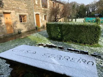 a bench covered in snow in front of a building at Casa Ferreiro - Campo da Cruz - Lugo in Baltar