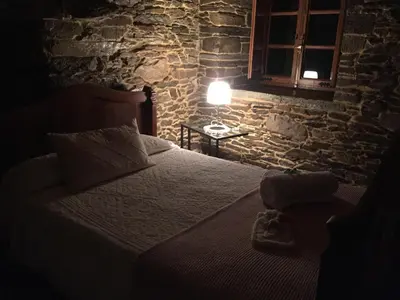 a bedroom with a bed in a stone walled room at Casa Ferreiro - Campo da Cruz - Lugo in Baltar