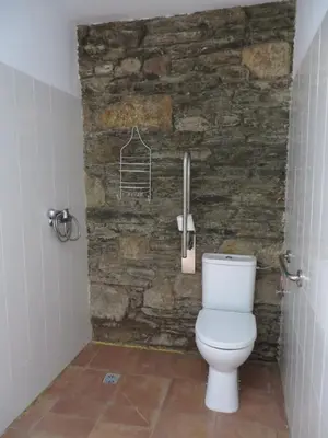 a bathroom with a toilet and a stone wall at Obradoiro in Sarria