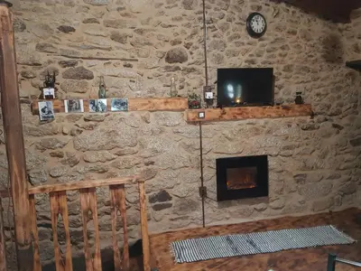 a stone wall with a television and a fireplace at A Paragűeria in Sas de Penelas
