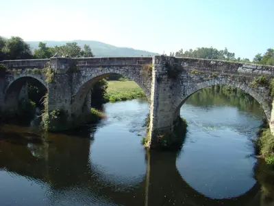an old stone bridge over a river at PR Albeitaría in Reis