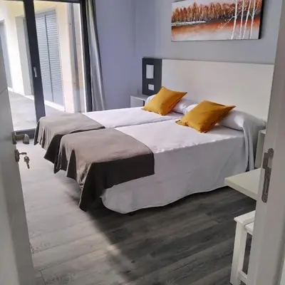 a bedroom with two beds with white sheets and yellow pillows at Carballos Altos-Apartamentos Turísticos in Arzúa