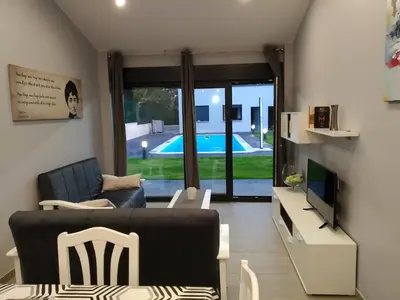 a living room with a couch and a television and a pool at Carballos Altos-Apartamentos Turísticos in Arzúa