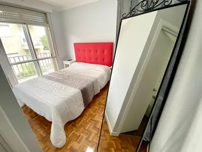 a bedroom with a red chair and a mirror at Garden Lodge Hostal Evencio in Ribadavia