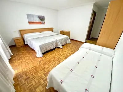 two beds in a room with wooden floors at Garden Lodge Hostal Evencio in Ribadavia