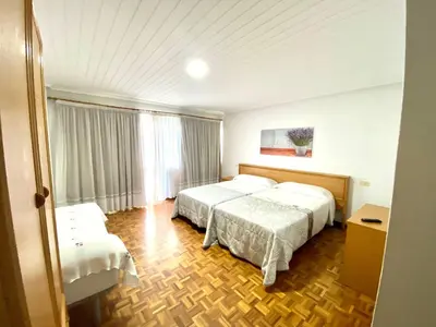 a hotel room with two beds and a window at Garden Lodge Hostal Evencio in Ribadavia