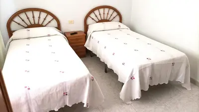 two beds in a room with white linens at Garden Lodge Hostal Evencio in Ribadavia