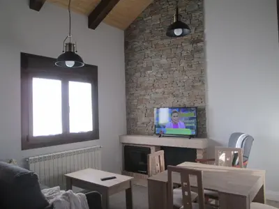 a living room with a tv and a brick wall at APARTAMENTOS FONTE VILLAR in Navia