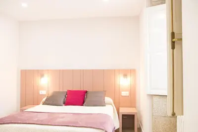 a bedroom with a bed with a pink pillow at Linares Rooms Santiago in Santiago de Compostela