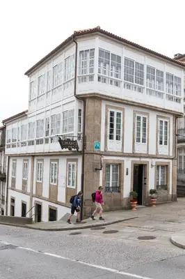 two people walking down a street in front of a building at Linares Rooms Santiago in Santiago de Compostela