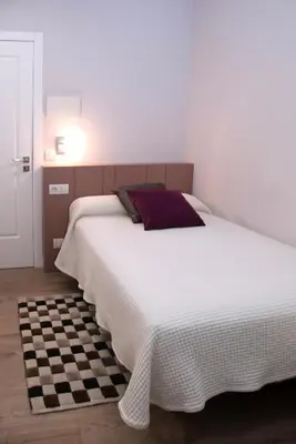 a bedroom with a large white bed with a checkered floor at Linares Rooms Santiago in Santiago de Compostela