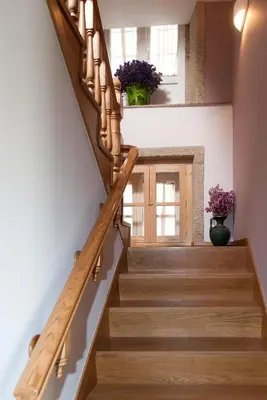 a staircase with wooden railings in a home with purple flowers at Linares Rooms Santiago in Santiago de Compostela
