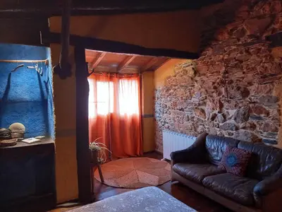 a living room with a couch and a stone wall at Louteiro de las Médulas in Orellán