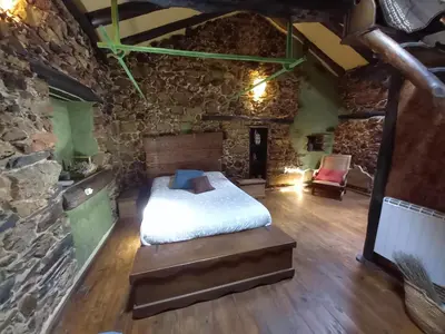 a bedroom with a bed and a stone wall at Louteiro de las Médulas in Orellán