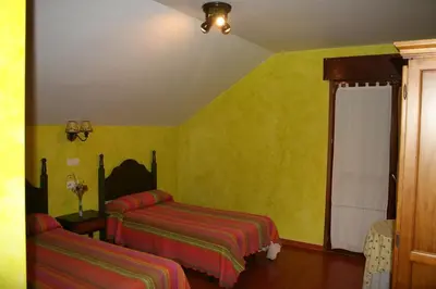 a bedroom with two beds and yellow walls at El Aposento De Babia in Quintanilla De Babia