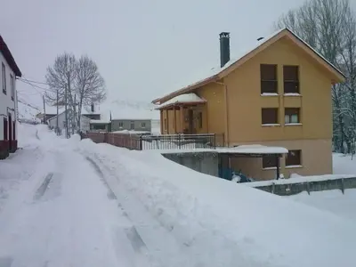 a snow covered road next to a house at El Aposento De Babia in Quintanilla De Babia