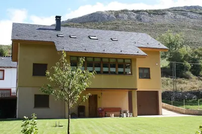 a house with a mountain in the background at El Aposento De Babia in Quintanilla De Babia