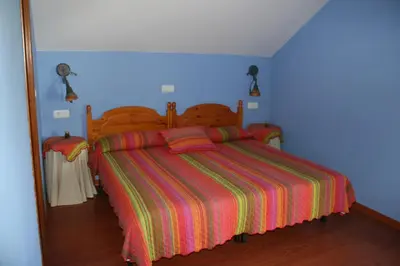 a bedroom with a bed with a colorful striped bedspread at El Aposento De Babia in Quintanilla De Babia