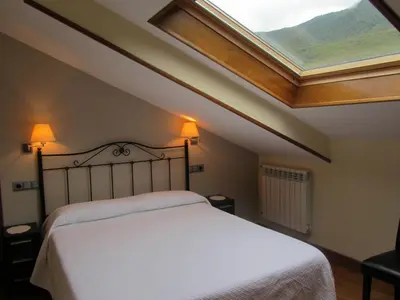 a bedroom with a large bed with a skylight at Apartamentos Rurales Casa Baltasar in Monasterio De Hermo