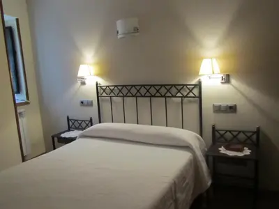a bedroom with a white bed with two night stands at Apartamentos Rurales Casa Baltasar in Monasterio De Hermo