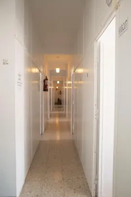 a hallway with white walls and a long hallway with white doors at Albergue Santa Olaia in Silleda