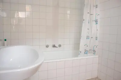 a white tiled bathroom with a sink and a tub at Albergue Santa Olaia in Silleda