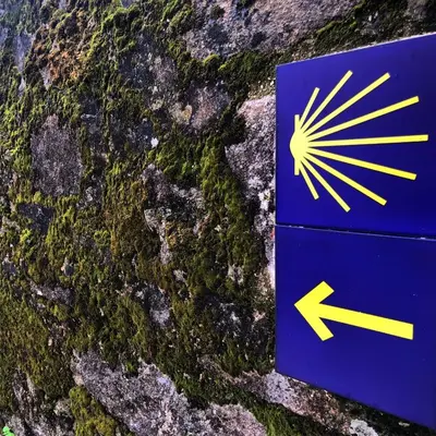 a sign with an arrow on a stone wall at Apartamento Padrón Centro P1 by URent in Padrón
