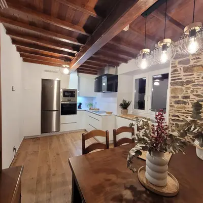 a kitchen and dining room with a table with a vase at Casa Tarrío con Piscina - Santiago de Compostela in Boqueijón