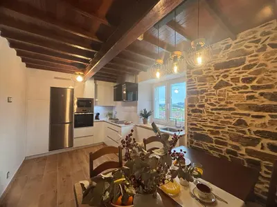 a kitchen and dining room with a stone wall at Casa Tarrío con Piscina - Santiago de Compostela in Boqueijón