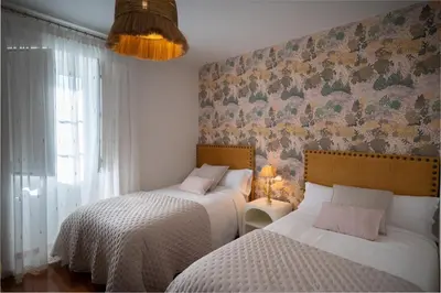 a bedroom with two beds and a wall with floral wallpaper at Casa Tarrío con Piscina - Santiago de Compostela in Boqueijón
