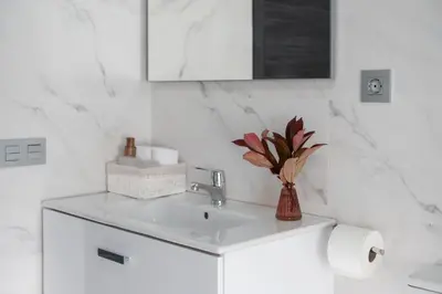 a white bathroom with a sink and a vase of flowers at Casa Tarrío con Piscina - Santiago de Compostela in Boqueijón
