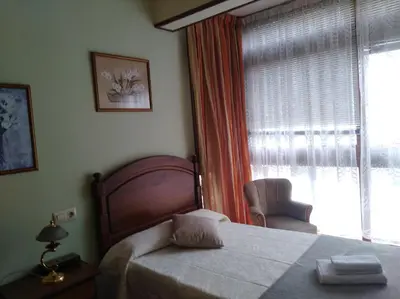 a bedroom with a bed and a window with a chair at jucar carmen in Santiago de Compostela