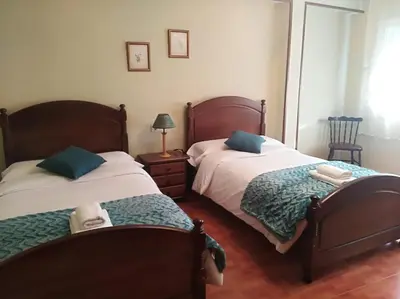 a bedroom with two beds and a table with a lamp at jucar carmen in Santiago de Compostela