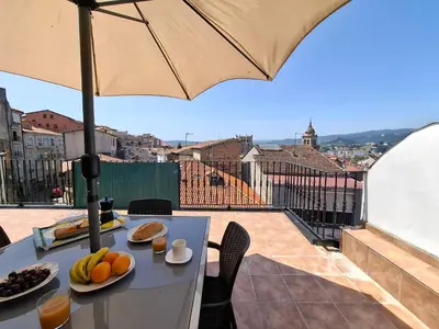 a table with fruit on it on a balcony with an umbrella at Luna - Disfruta de Ourense en este piso con terraza en el casco histórico in Ourense