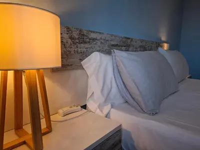 a bed with a lamp and a phone on a table at Luna - Disfruta de Ourense en este piso con terraza en el casco histórico in Ourense