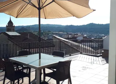 a table and chairs with an umbrella on a balcony at Luna - Disfruta de Ourense en este piso con terraza en el casco histórico in Ourense