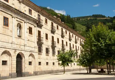 a large stone building with trees in front of it at Parador de Corias in Cangas del Narcea