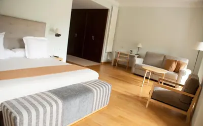 a hotel room with a bed and a couch and a chair at Parador de Corias in Cangas del Narcea