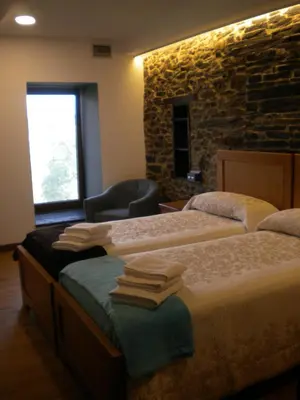 a bedroom with two beds and a stone wall at Casa de Aldea Araceli in Berducedo