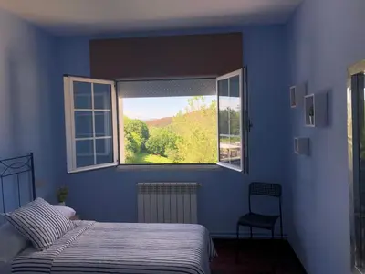 a blue bedroom with a bed and a window at Apartamento Ultreia in Palas de Rei