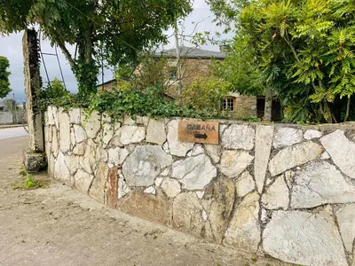 a stone retaining wall with a sign on it at Cabaña - A Pastoriza - Lugo in Baltar