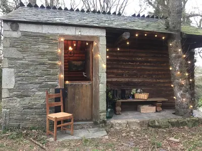 a log cabin with a wooden door and a wooden chair at Cabaña - A Pastoriza - Lugo in Baltar
